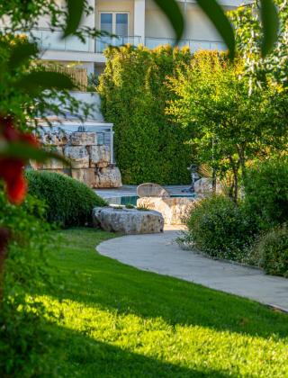 Garden with path, trees, and stones, serene atmosphere.